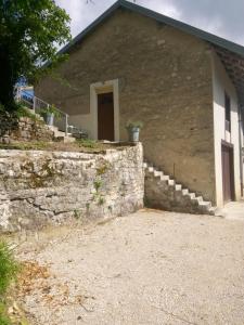 a building with a stone wall and a door at nature en petite montagne in Arinthod