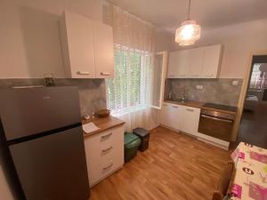 a kitchen with white cabinets and a black refrigerator at Apartmani Dvojak Njivice in Njivice