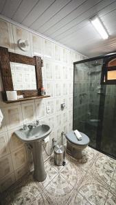 a bathroom with a shower and a sink and a toilet at Pousada Dona Ana in Monte Verde