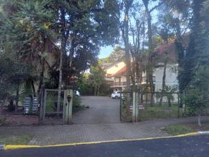 a gate to a driveway with a house at Casa com lareira em Gramado in Gramado