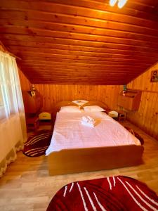 1 dormitorio con 1 cama grande en una habitación de madera en Casa de Vacanta Catrinel, en Ranca