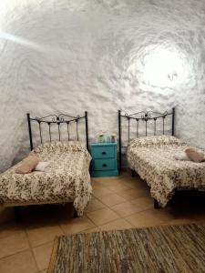 a bedroom with two beds and a blue table at Casa Cueva LA PARRA. in Terque