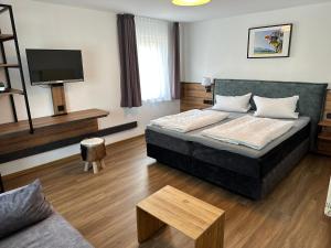 Habitación de hotel con cama y TV en Zum Bayrischen Wirt en Maierhöfen