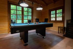 a pool table in a room with wooden walls and windows at Forest Amerika-Bungalovi Milica in Vrbovsko