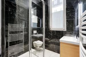 La salle de bains noire est pourvue de toilettes et d'un lavabo. dans l'établissement CMG Champs Elysées - Boetie 7, à Paris