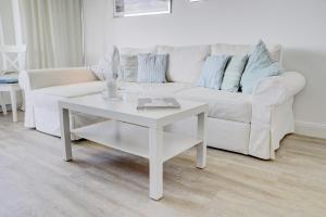 een witte woonkamer met een witte bank en een tafel bij fewo1846 - Fjordview - komfortables Studioapartment mit Balkon und Meerblick in Glücksburg