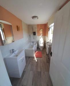a bathroom with a tub and a sink and a toilet at Pibble Cottage in Creetown