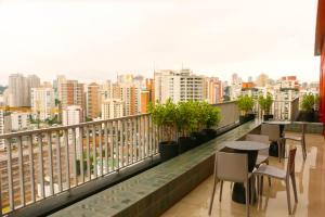 balcone con tavoli, sedie e vista sullo skyline della città di Apartamento Palmeiras a San Paolo