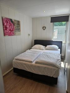 a bedroom with a large bed with white sheets and a window at Zomerhuis Duinzicht in Egmond aan den Hoef