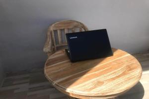 laptopa siedzącego na drewnianym stole w obiekcie OYO 92755 Abc Homestay w Labuan Bajo