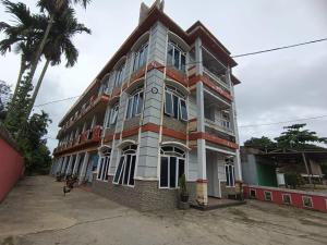 un gran edificio con una palmera delante en OYO 92751 Marang Homestay Syariah, 