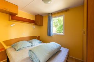 una piccola camera con letto e finestra di Camping des Templiers a Le Caylar