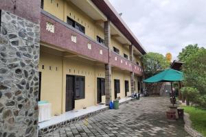 un edificio con sombrilla junto a un patio en OYO 92756 Kos Moncok en Tjakranegara