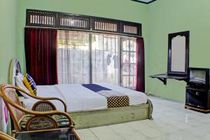 a bedroom with a bed in front of a window at SPOT ON 92682 Badar Guest House Syariah in Bandar Lampung