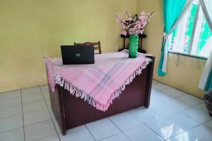 棉蘭的住宿－SPOT ON 92697 Ani Nur Homestay Syariah，一张桌子,上面有一台笔记本电脑,花瓶