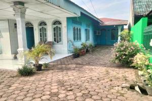 una casa azul y blanca con plantas delante en SPOT ON 92697 Ani Nur Homestay Syariah, en Medan