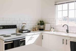 a white kitchen with a stove and a sink at The Studio Apartment - Nottingham Road in Nottingham Road