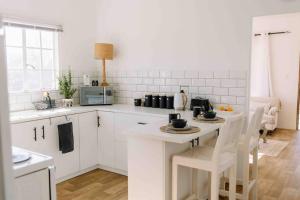 a kitchen with white cabinets and a table with chairs at The Studio Apartment - Nottingham Road in Nottingham Road