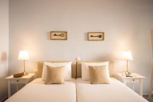 プラキアスにあるVilla Stella Suitesの白いベッド(ナイトスタンド2つ、ランプ2つ付)