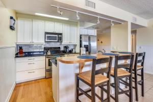 een keuken met witte kasten en een eiland met barkrukken bij Seahorse 401 in Clearwater Beach
