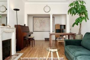 a living room with a green couch and a piano at Eiffel Tower Appartment in Paris