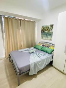 1 dormitorio con 1 cama con 2 almohadas verdes en Pahuwayan1 - an Urban Tropical Retreat, en Manila