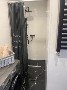 a bathroom with a shower with a black shower curtain at Apartament Mazurski Sen in Giżycko