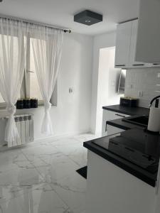 a kitchen with white walls and white counters and a window at Apartament Mazurski Sen in Giżycko