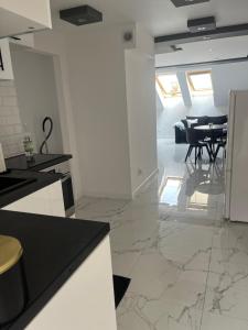 a kitchen with white walls and a dining room with a table at Apartament Mazurski Sen in Giżycko