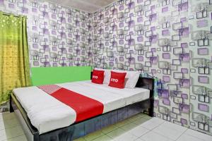 um quarto com uma cama com almofadas vermelhas em OYO 92759 Penginapan Piji Kembar em Karanganyar