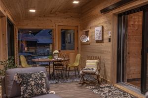 a porch with a table and chairs and a table and a table at Les 3 Cavaliers - Les Chalets Spa Canada in La Malbaie
