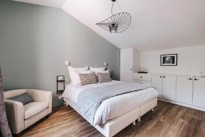 ein weißes Schlafzimmer mit einem Bett und einem Stuhl in der Unterkunft 64 Sur Le Mail in La Rochelle