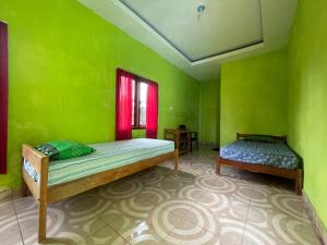 a green room with two beds and a window at SPOT ON 92766 Penginapan Asoka Indah in Barru