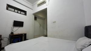 een slaapkamer met een wit bed en een televisie bij SPOT ON 92776 Panorama House in Tomohon