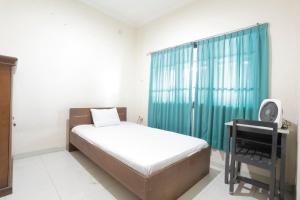 ein Schlafzimmer mit einem Bett und einem grünen Vorhang in der Unterkunft SPOT ON 92782 Rumah Kost Kita Tarakan in Tarakan