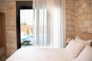 a bedroom with a white bed and a window at Pietra Mare Villas in Polychrono +65 photos