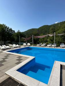 a swimming pool with chairs and mountains in the background at Vila Dzenana Boracko Jezero in Konjic