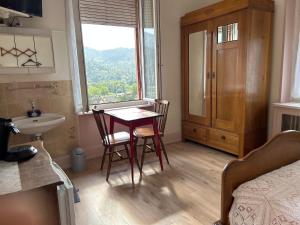 uma casa de banho com uma mesa e cadeiras e uma janela em Chambre Arnica lit 140 wifi sdb partagée em Saint-Amarin