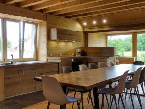 a kitchen with a large wooden table and chairs at Le chalet à comté in Saffloz
