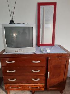 een tv bovenop een dressoir met een spiegel bij Casa de campo in Barra do Garças