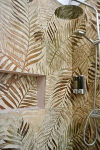 un baño con una pared con un mural de hojas en Novalis Rooms, en Porto Cesareo