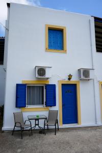 a building with a blue door and two chairs and a table at Green Parrot Apartments in Frátsia