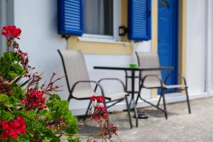 une table et des chaises sur une terrasse avec des fleurs rouges dans l'établissement Green Parrot Apartments, à Frátsia