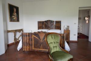 a bedroom with a bed and a green chair at La Casa di Penelope & Cirene in Pietrapertosa