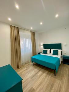 Un dormitorio con una cama azul y una ventana en Novalis Rooms, en Porto Cesareo