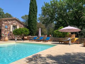 a swimming pool with chairs and an umbrella at Le Jas du Romarin in Callas