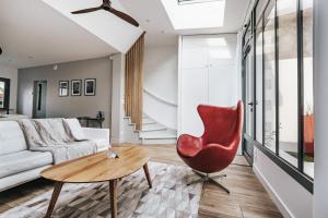 uma sala de estar com uma cadeira vermelha e um sofá em 64 Sur Le Mail em La Rochelle