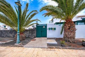 un edificio con una puerta verde y dos palmeras en Casa Costa Esmeralda-shared pool, en Costa Teguise