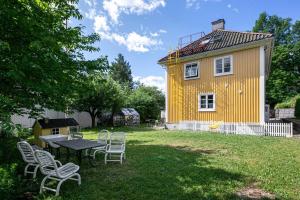 a yellow house with a table and chairs in the yard at Leilighet på Smestad in Oslo