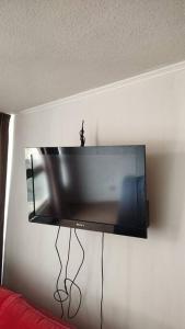 TV de pantalla plana colgada en la pared en Alojamiento frente a Turbus, en Santiago